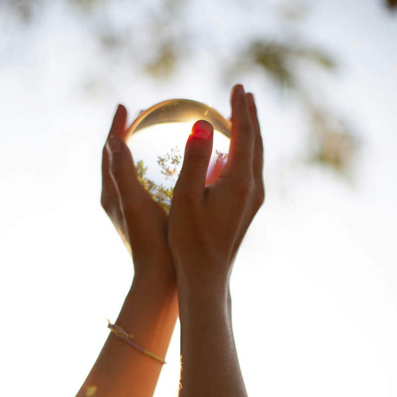 Rückansicht einer Frau die an einem See steht und die Arme über den Kopf streckt.Foto: Christopher Campbell via Unsplash