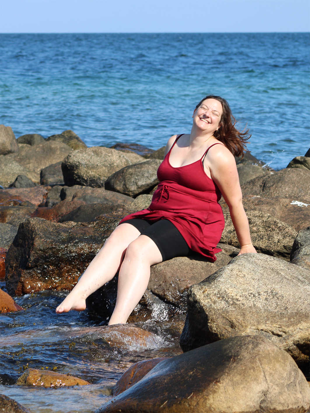Tesst sitzt auf einer Mole und planscht mit den Füßen im Wasser.